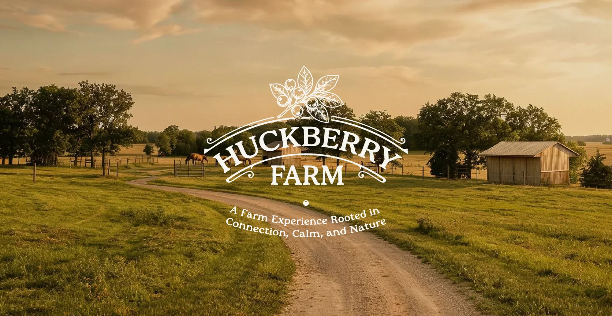 The Huckberry Farm primary crest over the pasture and gravel drive at golden hour
